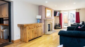 Un salon avec un meuble en bois, une cheminée, un canapé bleu et un téléviseur.
