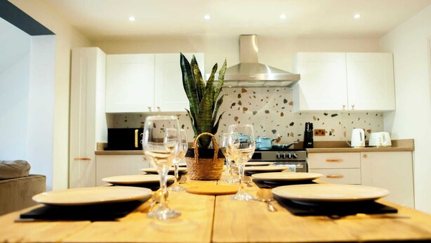 A modern kitchen with white cabinets, a central island with a woven basket, and a stainless steel range hood.