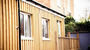 A wooden exterior with three windows and a small wooden deck.