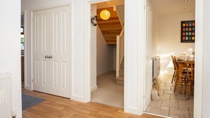 Ein Flur mit Holzboden, weißen Türen und einer Treppe zu einem Essbereich mit Tisch und Stühlen.