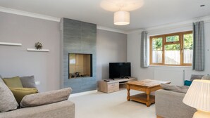 Ein modernes Wohnzimmer mit Flachbildfernseher, Couchtisch aus Holz und einer Couch.