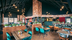 A spacious restaurant with high ceilings, exposed brick walls, and a variety of seating options including booths and tables.