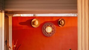 A room with a red wall, a wooden bench, a table with a vase, and a potted plant. - T3 Pisicine Chauffée et Privative (Saint-Leu)