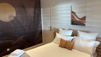 A bedroom with a bed, pillows, a wall mural, and a door.