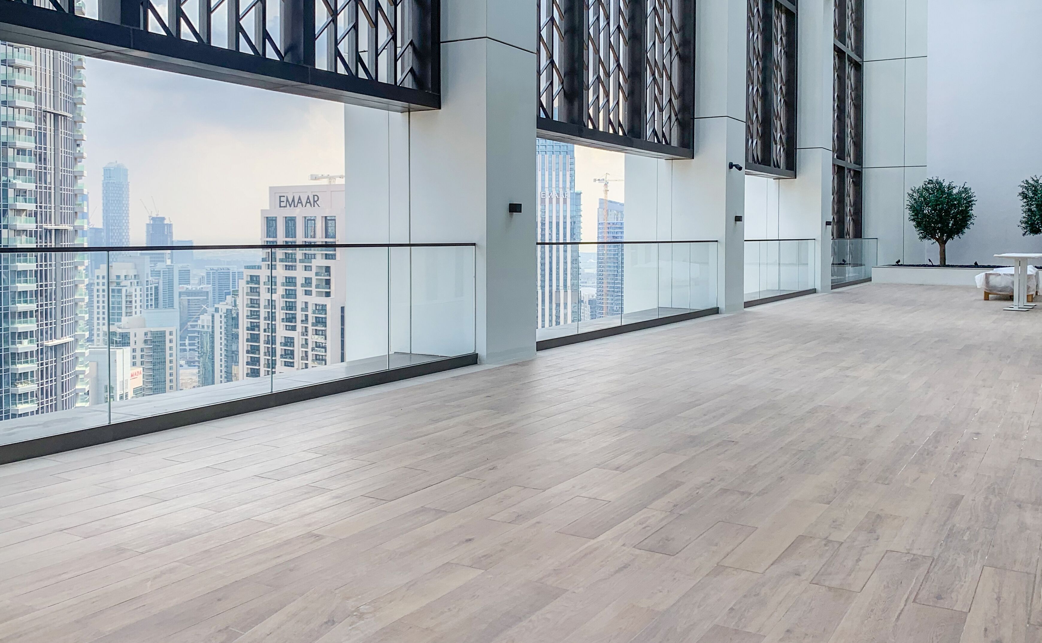 Un interior espacioso y moderno con grandes ventanales que ofrecen vistas de la ciudad, suelo de madera y diseño minimalista.