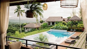 A poolside view with a thatched-roof house, lounge chairs, and a hanging light fixture. - La Joya Farm Resort & Spa (Aloguinsan)
