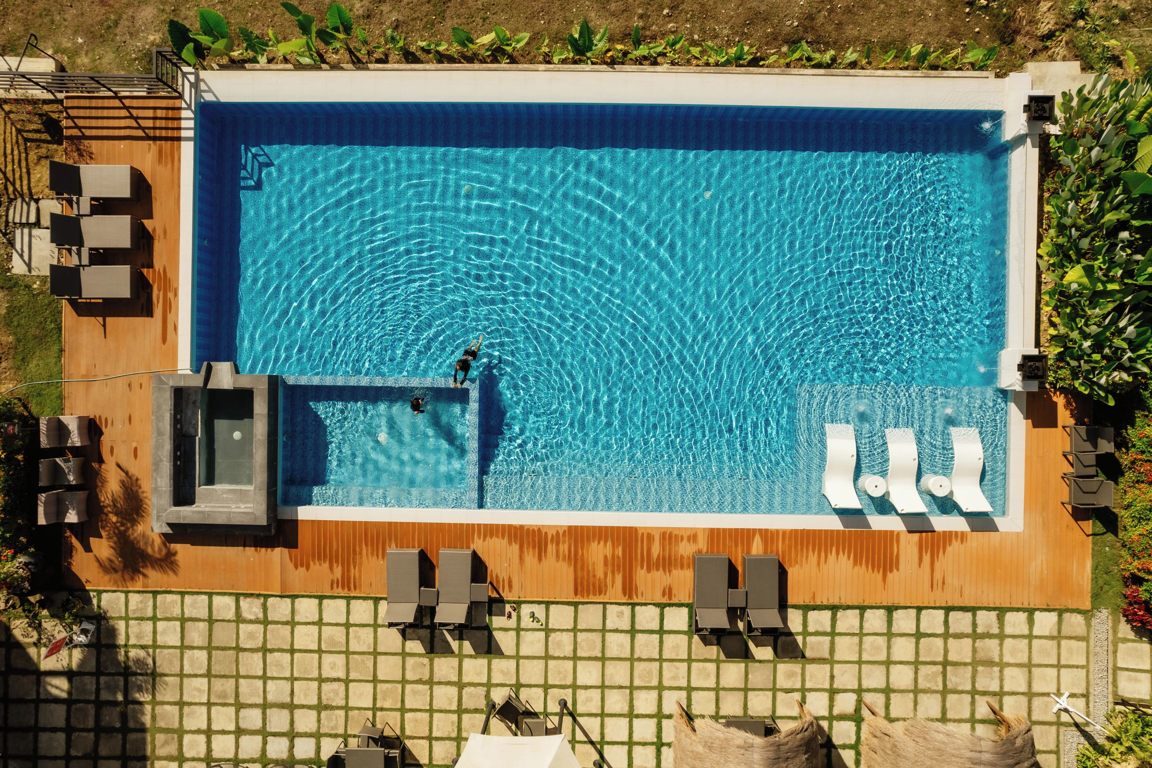 A rectangular swimming pool with a diving board and a small hot tub.