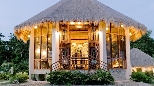 A thatched-roof building with a central staircase, surrounded by glass windows and a well-lit interior. - La Joya Farm Resort & Spa (Aloguinsan)