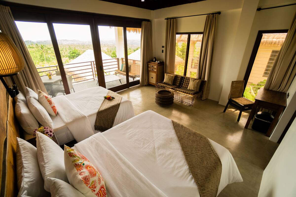 Habitación de hotel con dos camas, un sofá, una mesa de comedor y vistas al paisaje.