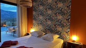 Un dormitorio con cama, dos lámparas de noche, una ventana con cortinas y vistas al exterior.