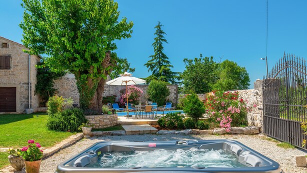 A hot tub in a backyard with a stone wall, a pool, and outdoor furniture. - 4 bedroom awesome home in Visnjan (Visnjan)