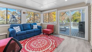 Ein Wintergarten mit einem blauen Sofa, einem roten Sessel und einem roten Teppich mit Muster.