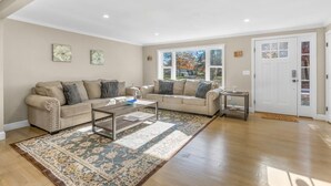 Ein geräumiges Wohnzimmer mit zwei beigefarbenen Sofas, einem Couchtisch und einem gemusterten Teppich.