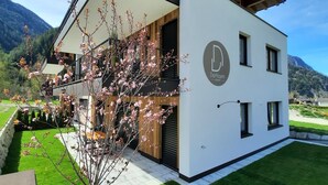 A modern two-story building with a balcony, a logo on the side, and a well-maintained lawn.