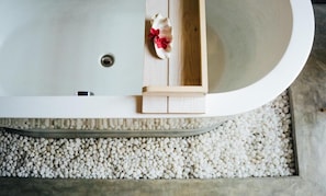 Una bañera con una bandeja de madera y una flor roja decorativa.