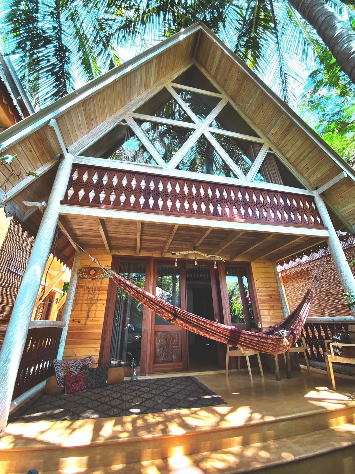 A wooden building with a sloped roof, a hammock, and a wooden door.