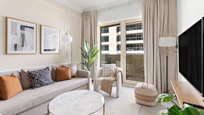 A modern living room with a sofa, armchair, ottoman, and a flat-screen TV. - Silkhaus Manchester Tower, Dubai Marina (Dubai)