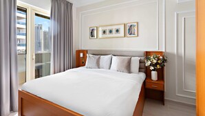 A hotel room with a large bed, a nightstand with a vase of flowers, and a view of the city through the window. - Silkhaus Manchester Tower, Dubai Marina (Dubai)