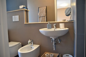 A bathroom with a sink, bidet, toilet, and a mirror.