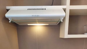 A modern kitchen with a built-in stove, a white range hood, and a small sink.