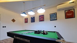 Ett biljardbord med en etikett som säger ”American Fitness”, omgivet av inramade sportminnessaker på väggen.