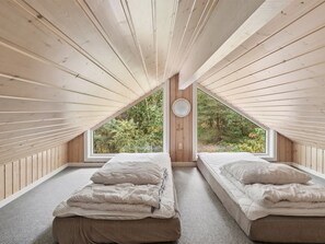 A bedroom with two beds, a window, and a view of trees.