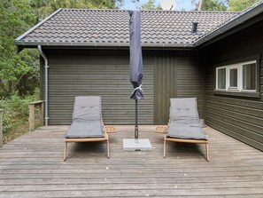 A wooden deck with two lounge chairs and a covered umbrella.