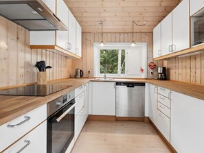 A modern kitchen with wooden cabinets, stainless steel appliances, and a window providing a view of greenery.