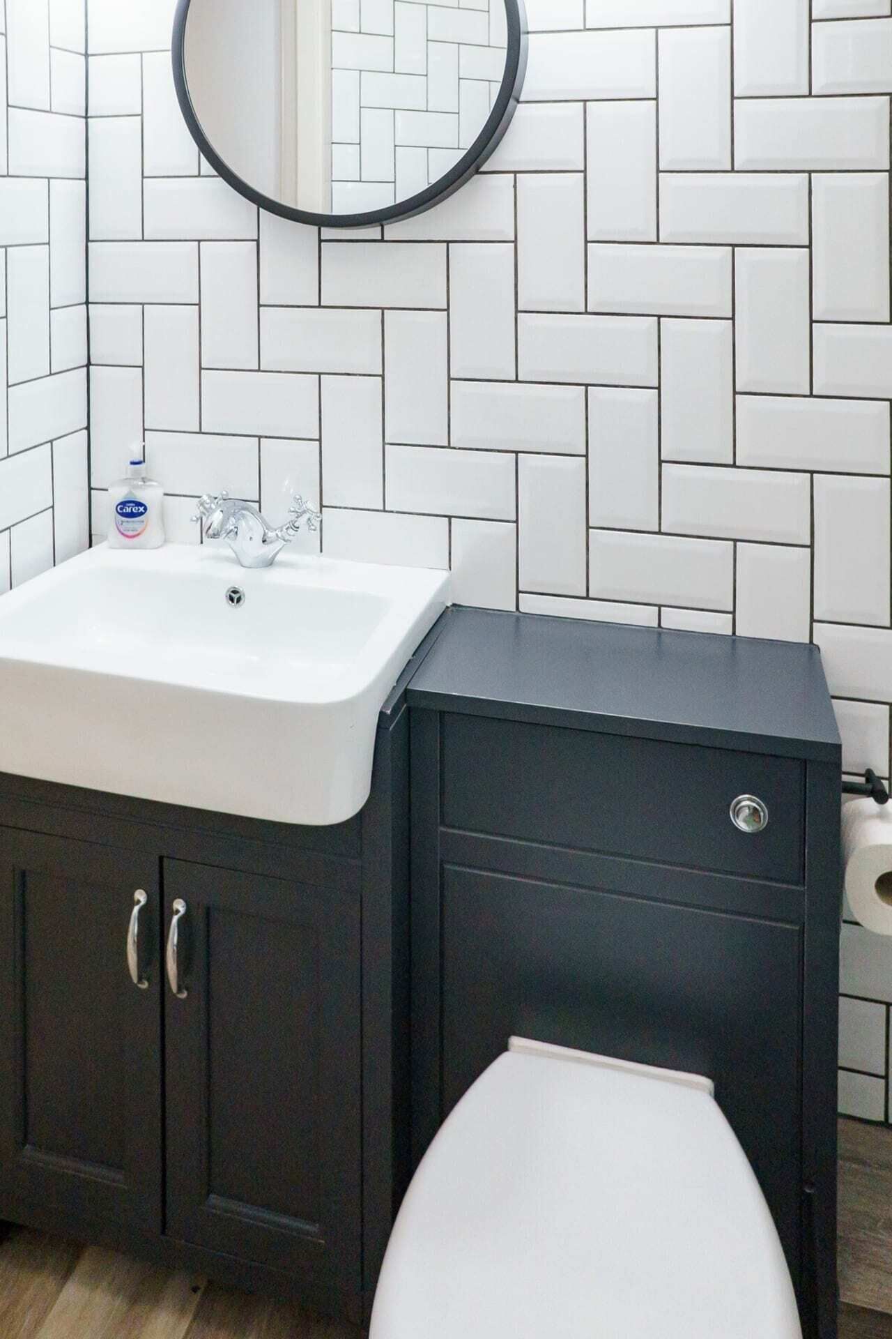 Une salle de bain avec un lavabo blanc, un meuble sombre et des toilettes.