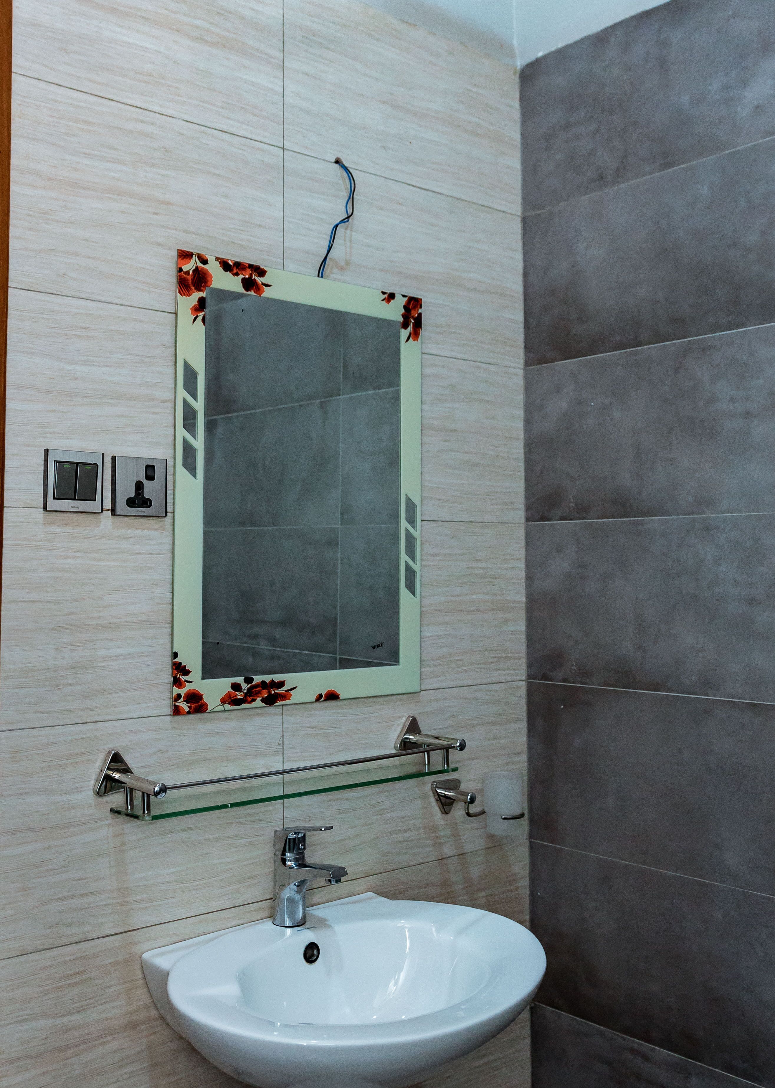 A bathroom with a white sink, a mirror with a floral frame, and a towel rack.