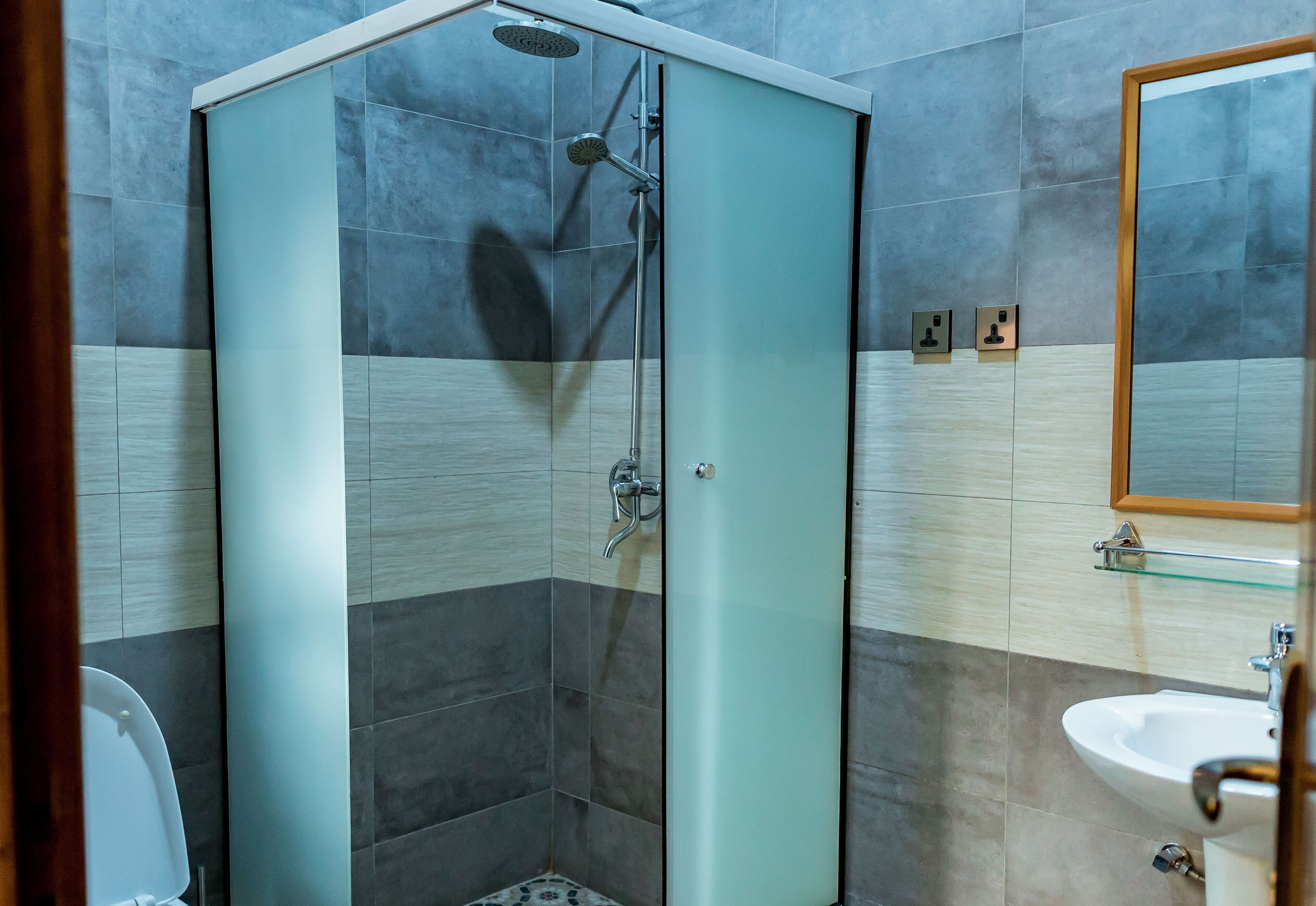 Een moderne badkamer met een douchecabine van glas, een wastafel en een spiegel.