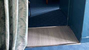 A hotel room with a bed, bedside table, and a small desk.