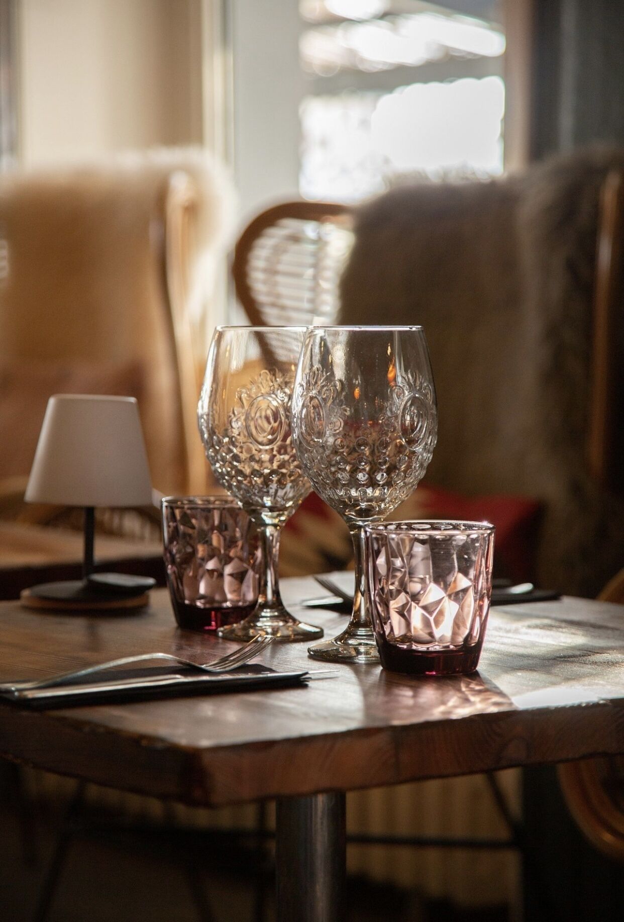 Una mesa con tres vasos de cristal y una lámpara pequeña.