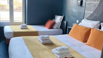 Habitación de hotel con dos camas, un ventanal grande y un aire acondicionado de pared.