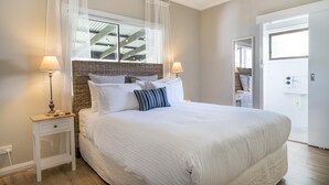 A neatly arranged bedroom with a large bed, two bedside tables, and a window with sheer curtains. - Seafarers Cottage - A Dog's Dream on the Mornington Peninsula! (Capel Sound)