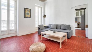A living room with a grey sofa, a wooden coffee table, and a woven pouf.