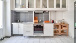 A modern kitchen with white cabinets, a built-in oven, and a wooden countertop.