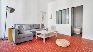 A modern living room with a grey sofa, a wooden coffee table, a floor lamp, and a large window.