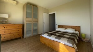 A bedroom with a wooden bed, a dresser, a wardrobe, and a bedside lamp.
