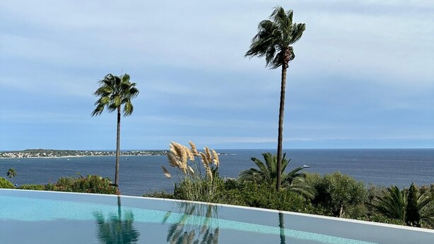 A clear blue sky, a swimming pool, and a view of the ocean.