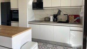 A modern kitchen with white cabinets, a black range hood, and a wooden countertop.