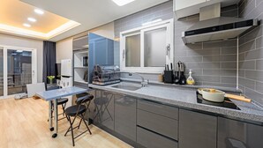 A modern kitchen with grey cabinets, a stainless steel range hood, and a built-in dishwasher. - Anmyeondo Town 1967 Dog Pool Villa (Taean)