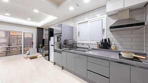 A modern kitchen with grey cabinets, a built-in oven, and a large window. - Anmyeondo Town 1967 Dog Pool Villa (Taean)