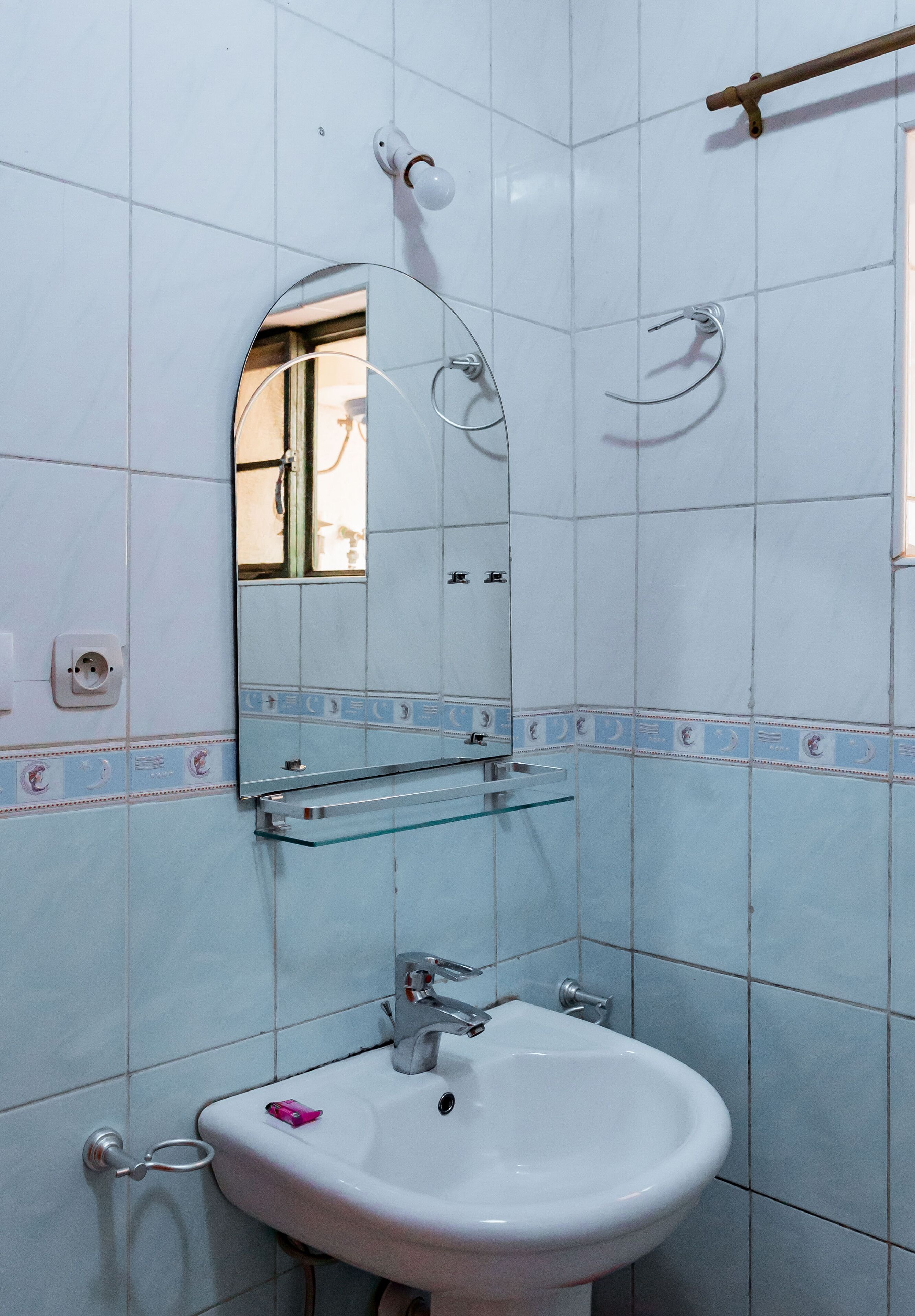 A bathroom with a white sink, a mirror, and a towel rack.