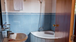Een badkamer met een wastafel, een bad en een douche.