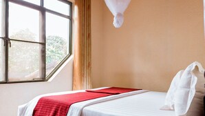 Een slaapkamer met een bed, een raam en een klamboe.