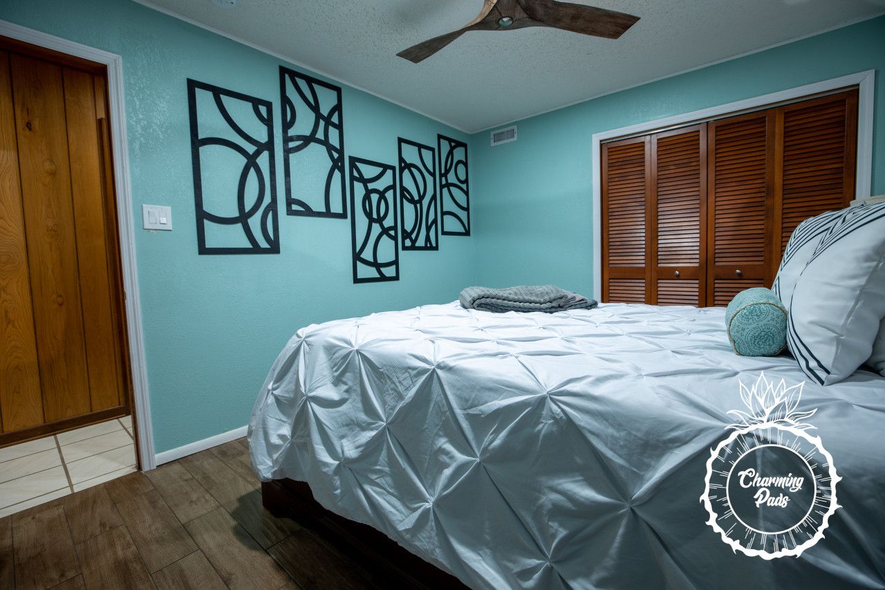Quarto com cama, armário de madeira e obras de arte na parede.