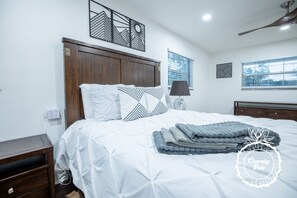 A neatly made bed with white and black patterned pillows, a folded gray blanket, and a bedside table with a lamp. - Winter Park Charmer - Heated Pool Home - Close to everything (Winter Park)