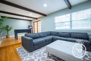 A modern living room with a sectional sofa, a coffee table, and a piano.