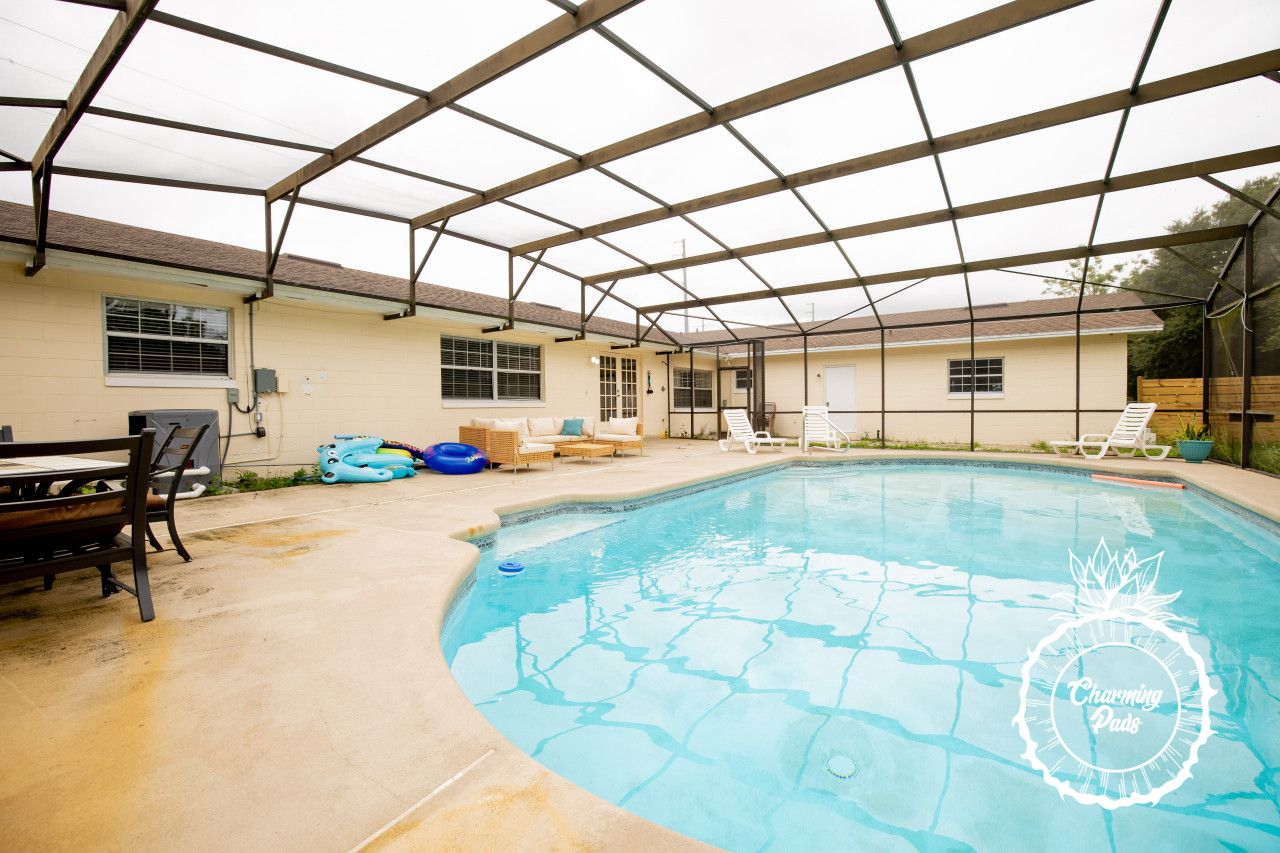 Uma área de piscina ao ar livre coberta, com espreguiçadeiras e uma mesa.